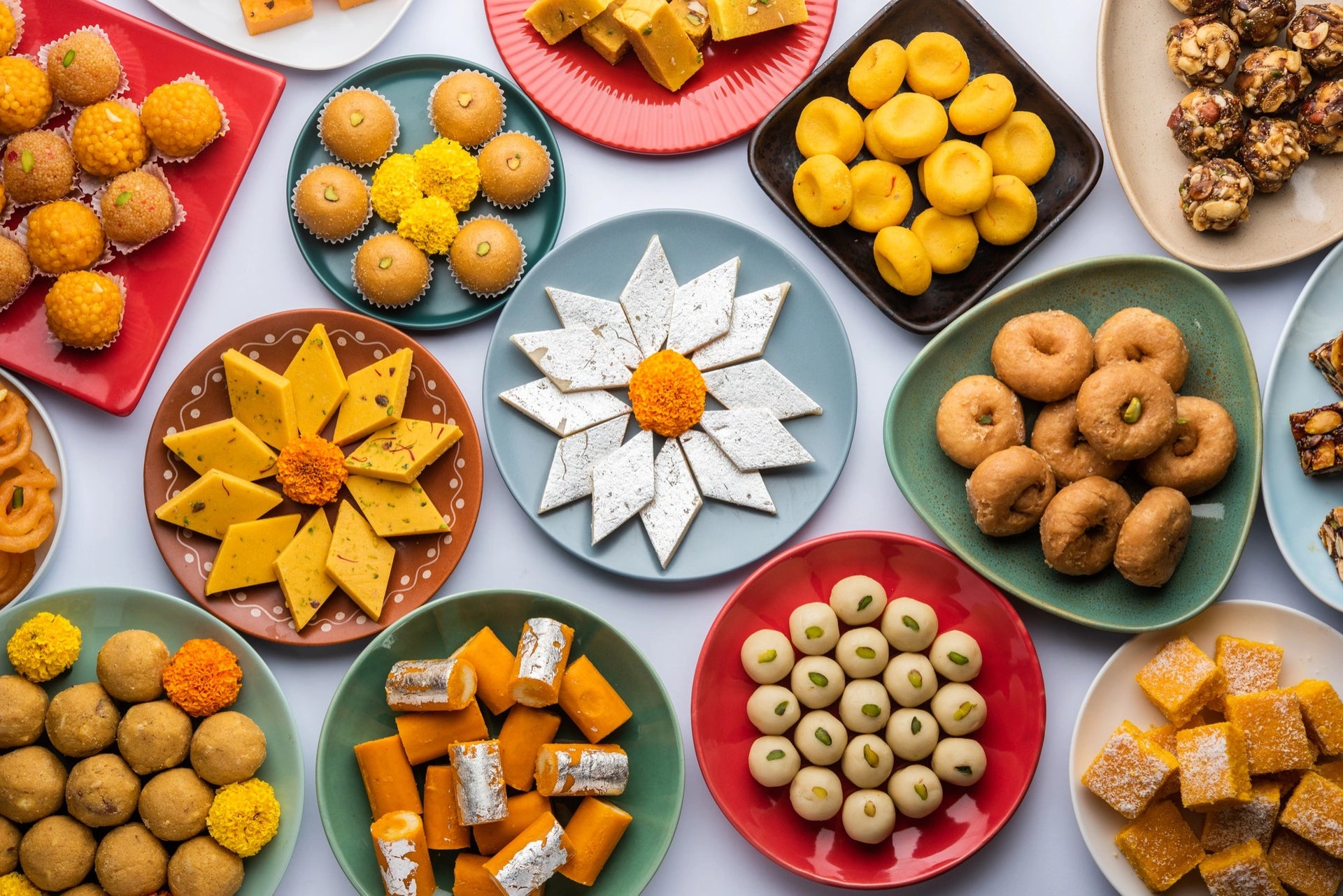Assorted traditional sweets on colorful plates on a white background